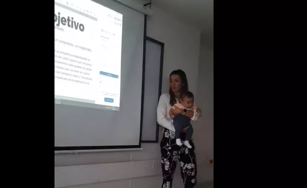 Profesora carga al bebé de una alumna para que ella pueda tomar clase.