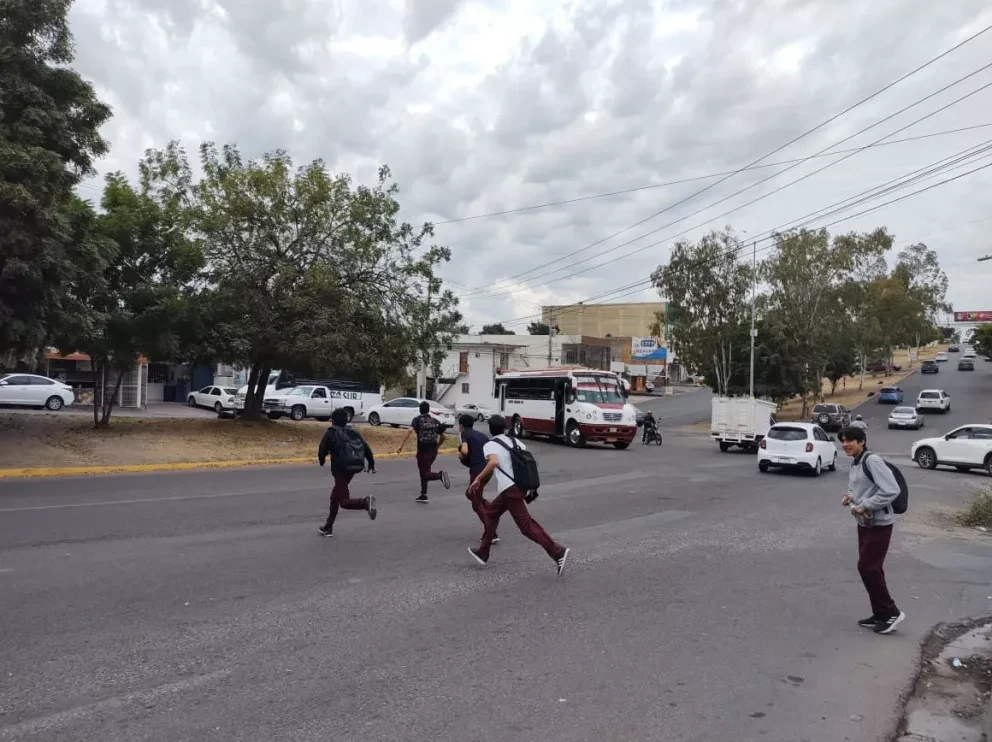 Momento en que estudiantes cruzan corriendo el cruce de la avenida Manuel Clouthier y Cerro de las Cumbres en el sector Loma Linda. Fotos: Juan Madrigal