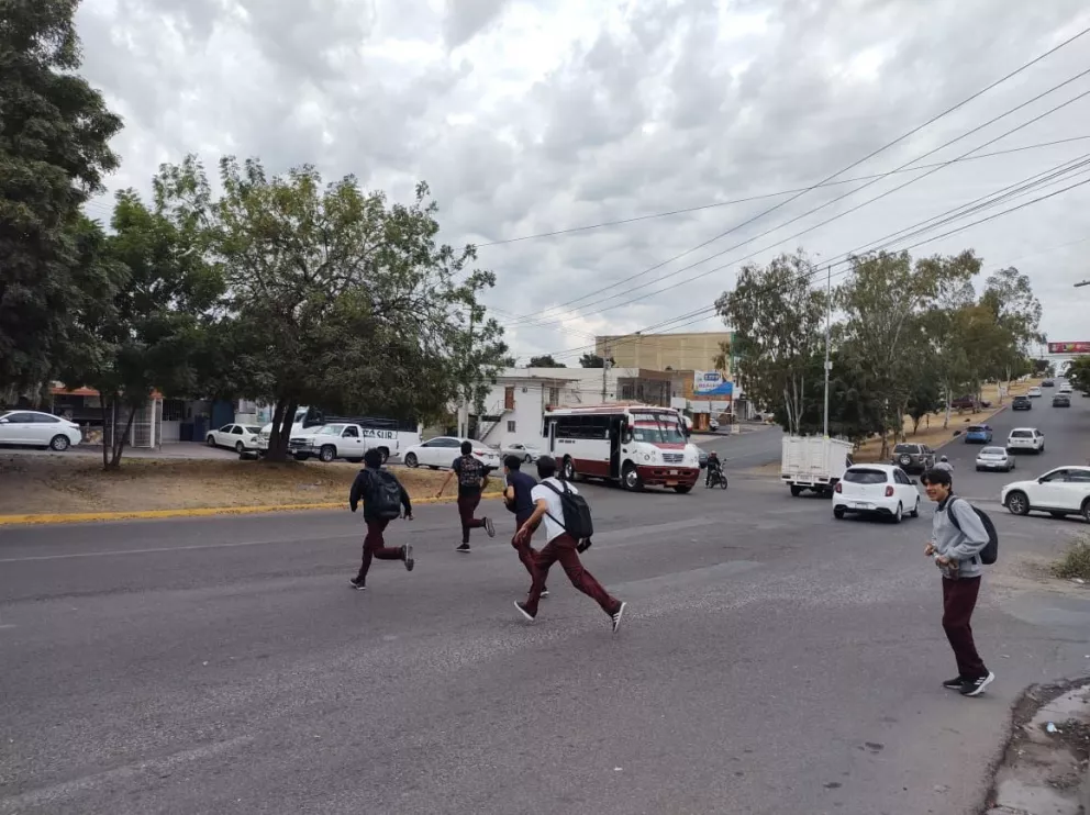 Momento en que estudiantes cruzan corriendo el cruce  de la avenida Manuel Clouthier y Cerro de las Cumbres en el sector Loma Linda. Fotos: Juan Madrigal
