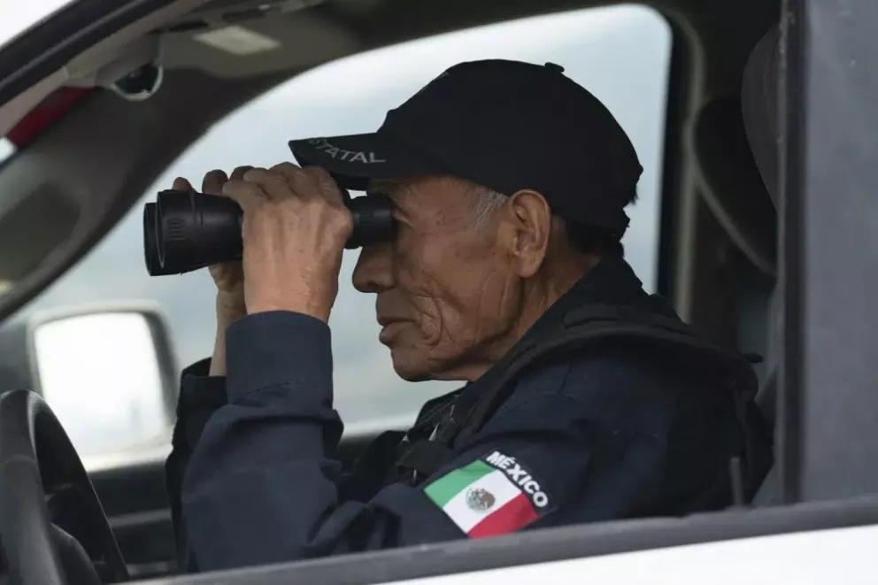 Nefi de Aquino, quien trabaja como oficial de policía y también vigila la actividad del Popocatépetl, observa el volcán a través de sus binoculares desde Santiago Xalitzintla, México, el jueves 25 de mayo de 2023. (AP Foto/Marco Ugarte)
