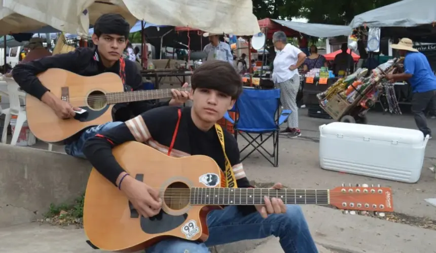 Virlan y Brandon, salen con su guitarra para alegrar a las personas, quienes en agradecimiento les regalan una moneda que les ayuda a pagar sus estudios. Fotos: Juan Madrigal