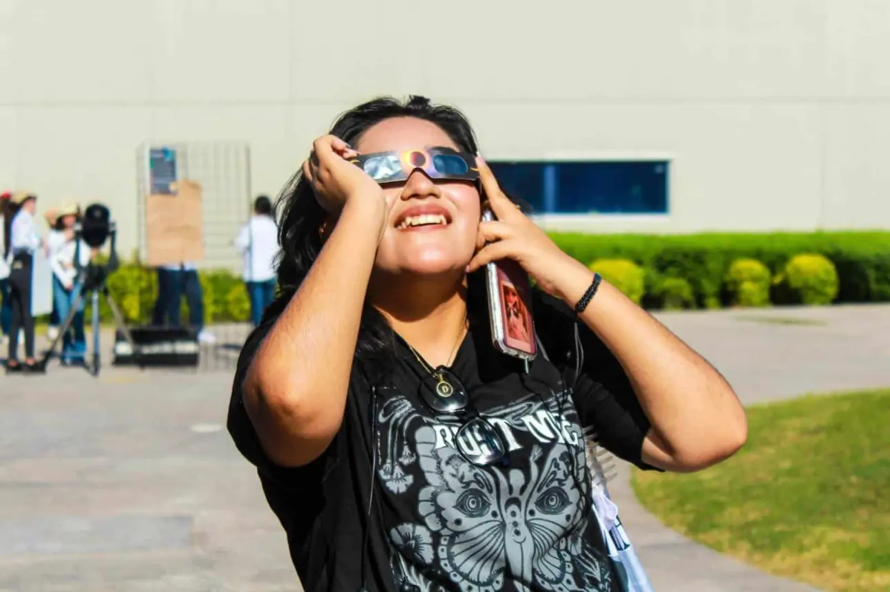 Niña observando un eclipse con lentes adecuados.