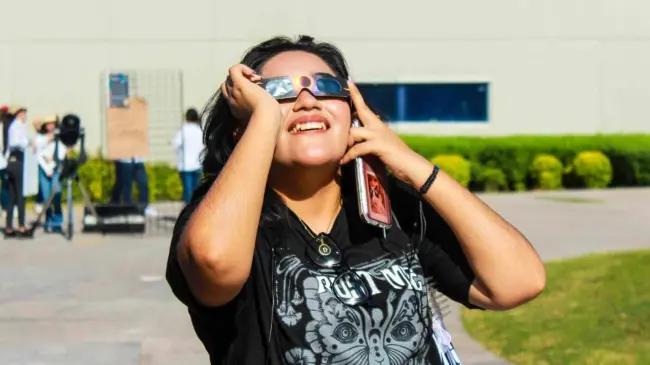 Niña observando un eclipse con lentes adecuados.