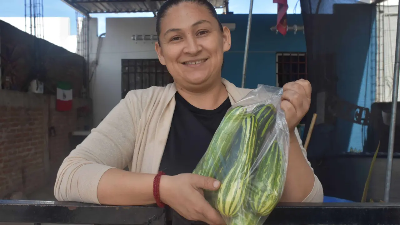 De muy buen ánimo Lupita vende sus calabazas en la puerta de su hogar.
