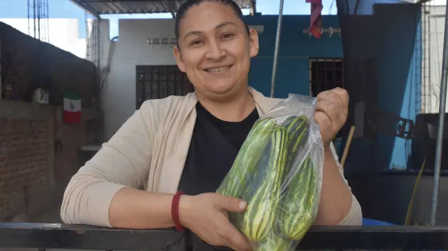 De muy buen ánimo Lupita vende sus calabazas en la puerta de su hogar.