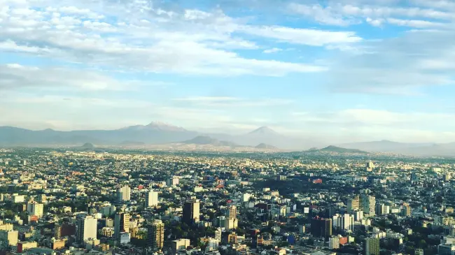 Imagen aérea de la Ciudad de México de día.  Foto de <a href=https://unsplash.com/es/@alexistostado?utm_content=creditCopyText&utm_medium=referral&utm_source=unsplash>Alexis Tostado</a> en <a href=https://unsplash.com/es/fotos/foto-aerea-de-edificios-de-hormigon-bajo-nubes-blancas-durante-el-dia-3TBuSLluZ8w?utm_content=creditCopyText&utm_medium=referral&utm_source=unsplash>Unsplash</a>