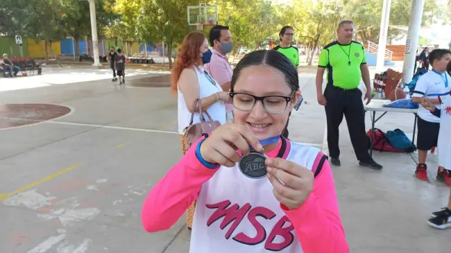 Muy emocionada Analu recibe sus medallas como basquetbolista.