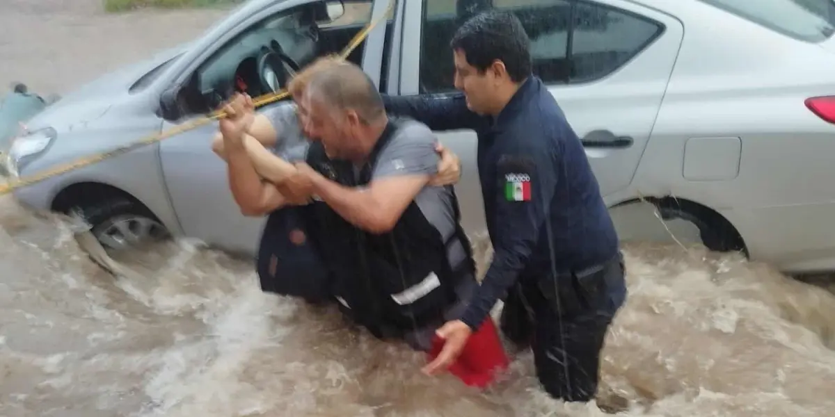 Elementos de corporaciones de seguridad ponen a salvo a mujer atrapada en vehículo que era arrastrado por corriente de agua en la colonia Industrial El Palmito en Culiacán. Foto: SSPyM