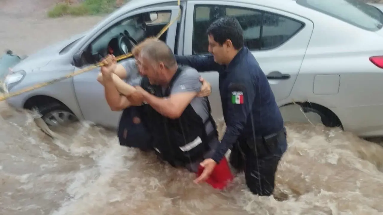 Elementos de corporaciones de seguridad ponen a salvo a mujer atrapada en vehículo que era arrastrado por corriente de agua en la colonia Industrial El Palmito en Culiacán. Foto: SSPyM
