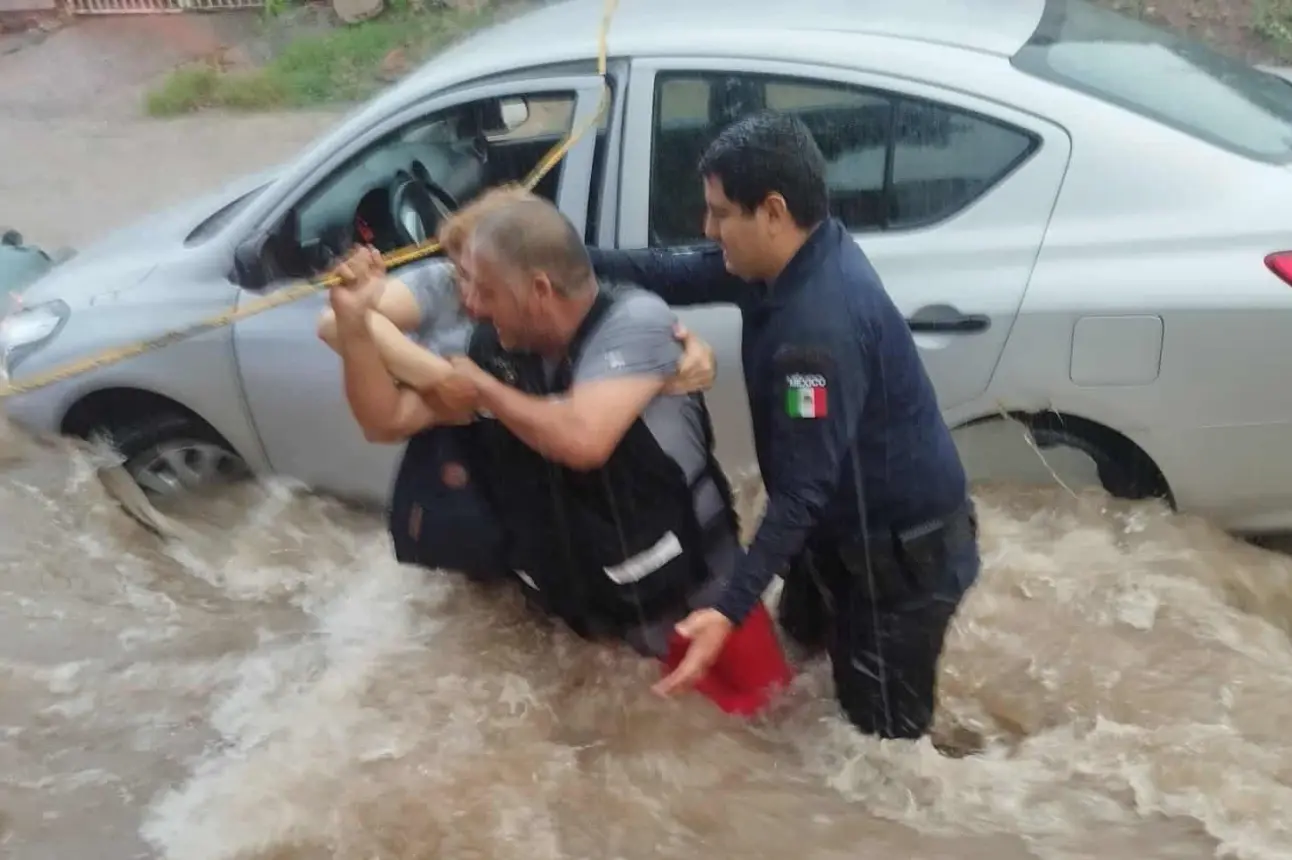 Elementos de corporaciones de seguridad ponen a salvo a mujer atrapada en vehículo que era arrastrado por corriente de agua en la colonia Industrial El Palmito en Culiacán. Foto: SSPyM