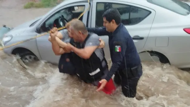 Elementos de corporaciones de seguridad ponen a salvo a mujer atrapada en vehículo que era arrastrado por corriente de agua en la colonia Industrial El Palmito en Culiacán. Foto: SSPyM