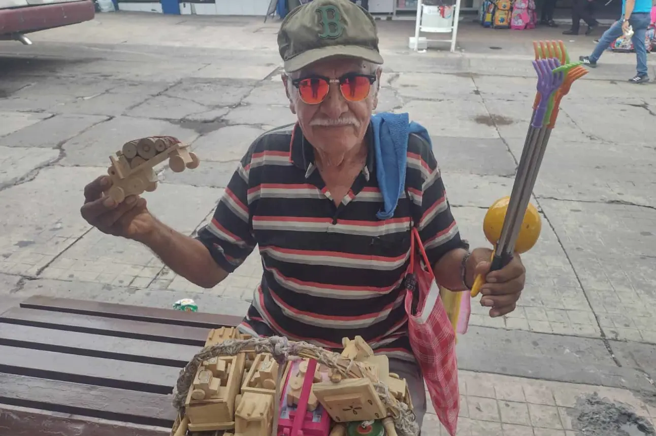 Don Lalo vende sus carritos de madera. Alegra a los niños de la ciudad y su corazón se llena de dicha cada día.