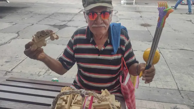 Don Lalo vende sus carritos de madera. Alegra a los niños de la ciudad y su corazón se llena de dicha cada día.
