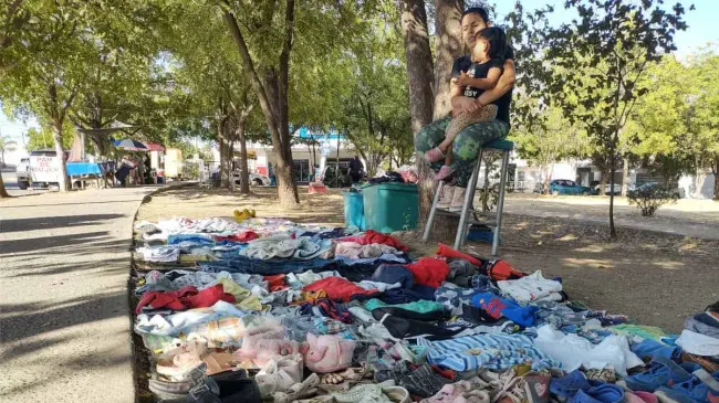 Marlén Muñoz, acompañada de su hija de 2 años, atiende su puesto de venta de ropa en un parque de Los Ángeles. Foto: Francisco Castro