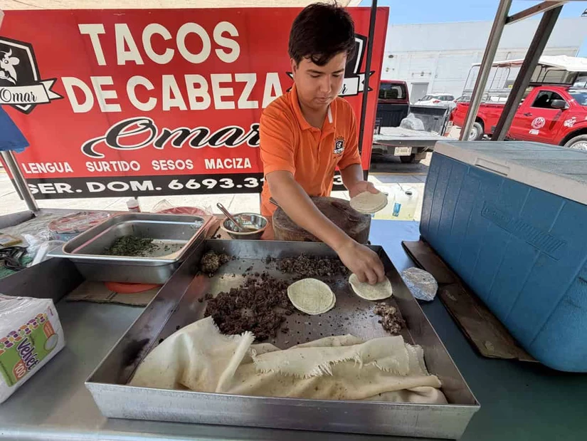 Juan Pablo atiende con gusto a la clientela en su carreta de tacos de cabeza todas las mañanas a las afueras del estacionamiento de la Bodega Aurrerá de Pradera Dorada