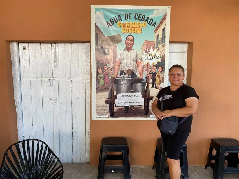 Con orgullo, Sonia Iveth posa junto a la imagen animada del su abuelo Sotero, quien le heredo la tradición de la venta de agua de horchata
